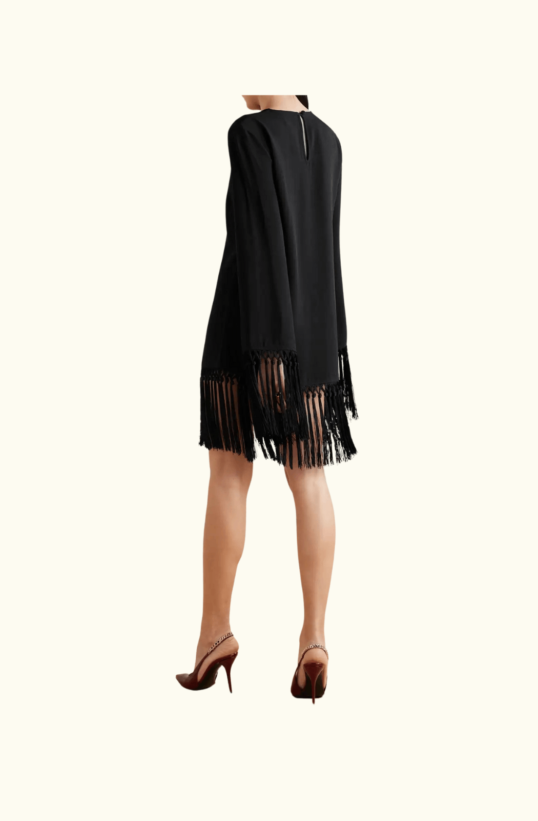 A back view of the Taller Marmo 'Claudia' mini dress in black, featuring long sleeves and dramatic fringe detailing along the hem and cuffs. The dress is paired with sleek stiletto heels.