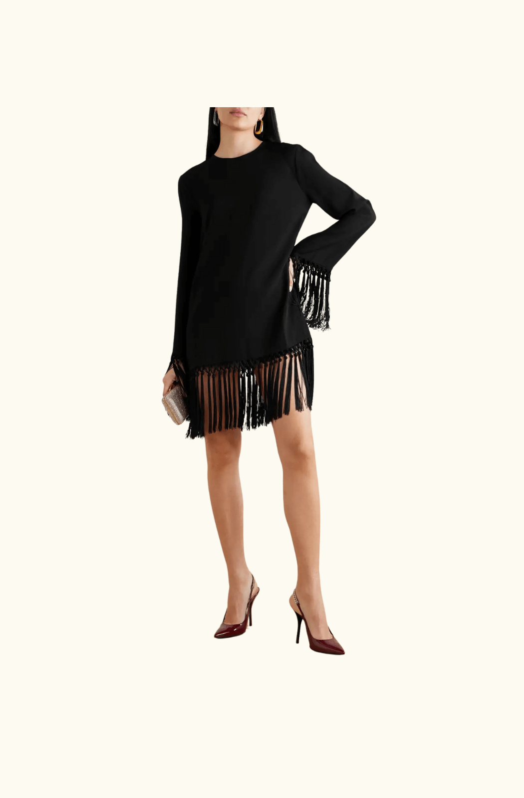 A model wearing the Taller Marmo 'Claudia' mini dress in black. The outfit highlights the swinging fringe details on the sleeves and hem, paired with burgundy heels and statement earrings.