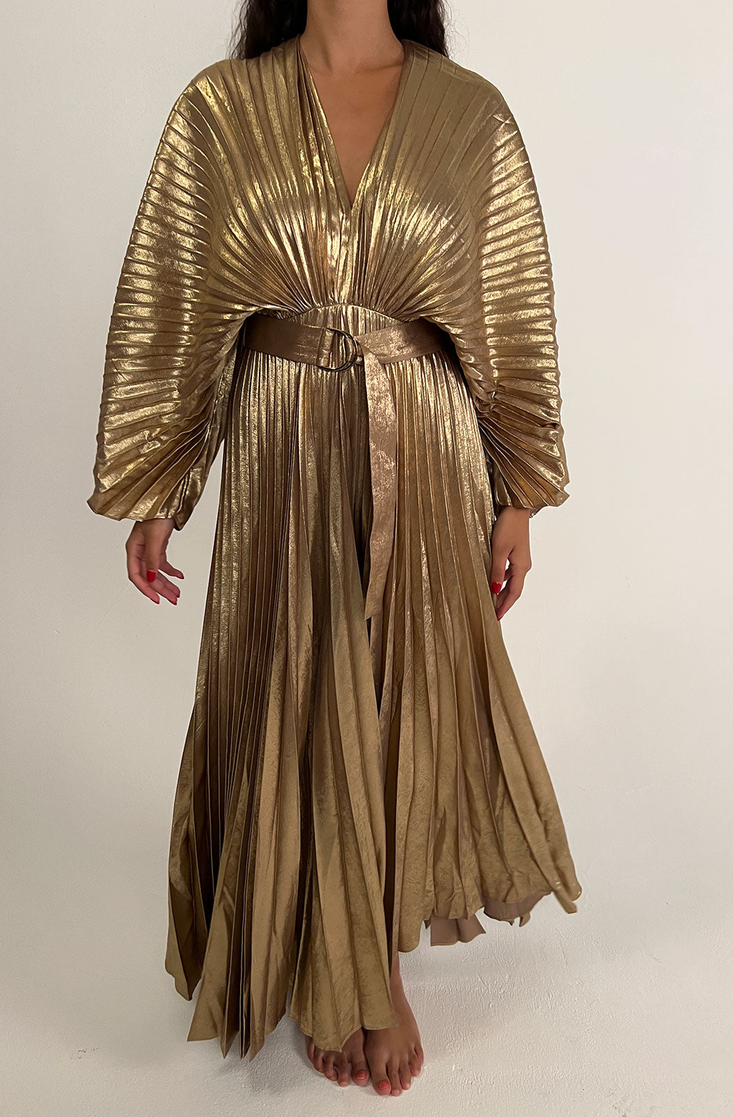 Acler Women's Natural Westover Dress The Westover Dress in Gold by Acler is a maxi dress crafted in a gold pleated fabrication featuring full length sleeves, a plunging neckline, open back, and statement belt. 100% Polyester.