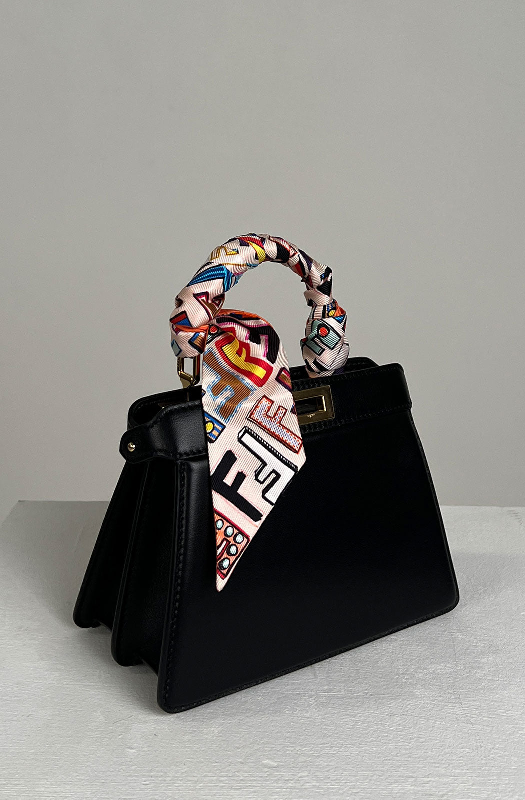 Iconic small Peekaboo bag made of black Cuoio Romano leather, embellished with hand stitching and the classic twist lock on both sides.