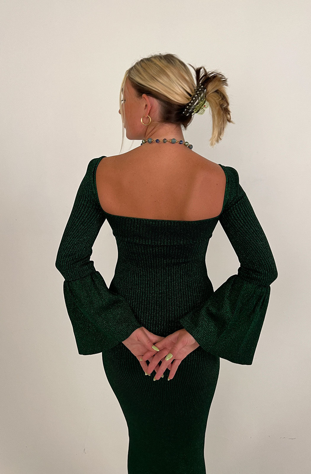 the Ribbed Bow Bust Midi Dress back view from self Portrait. Designed with a sweetheart neckline and long sleeves, this dress is characterised by puffed shoulders and flared cuffs to the ends of the sleeves. Cut to a midi length in a ribbed construction, this dress is finished with a bow detail to the bust with a sultry cut out to the middle.