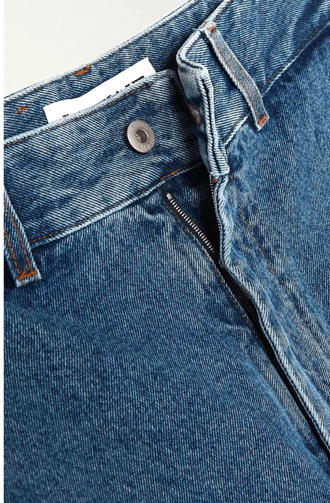 Close-up detail of the Loewe Anagram Appliquéd Jeans showing the button closure, zip fly, and texture of the mid-weight blue denim fabric.