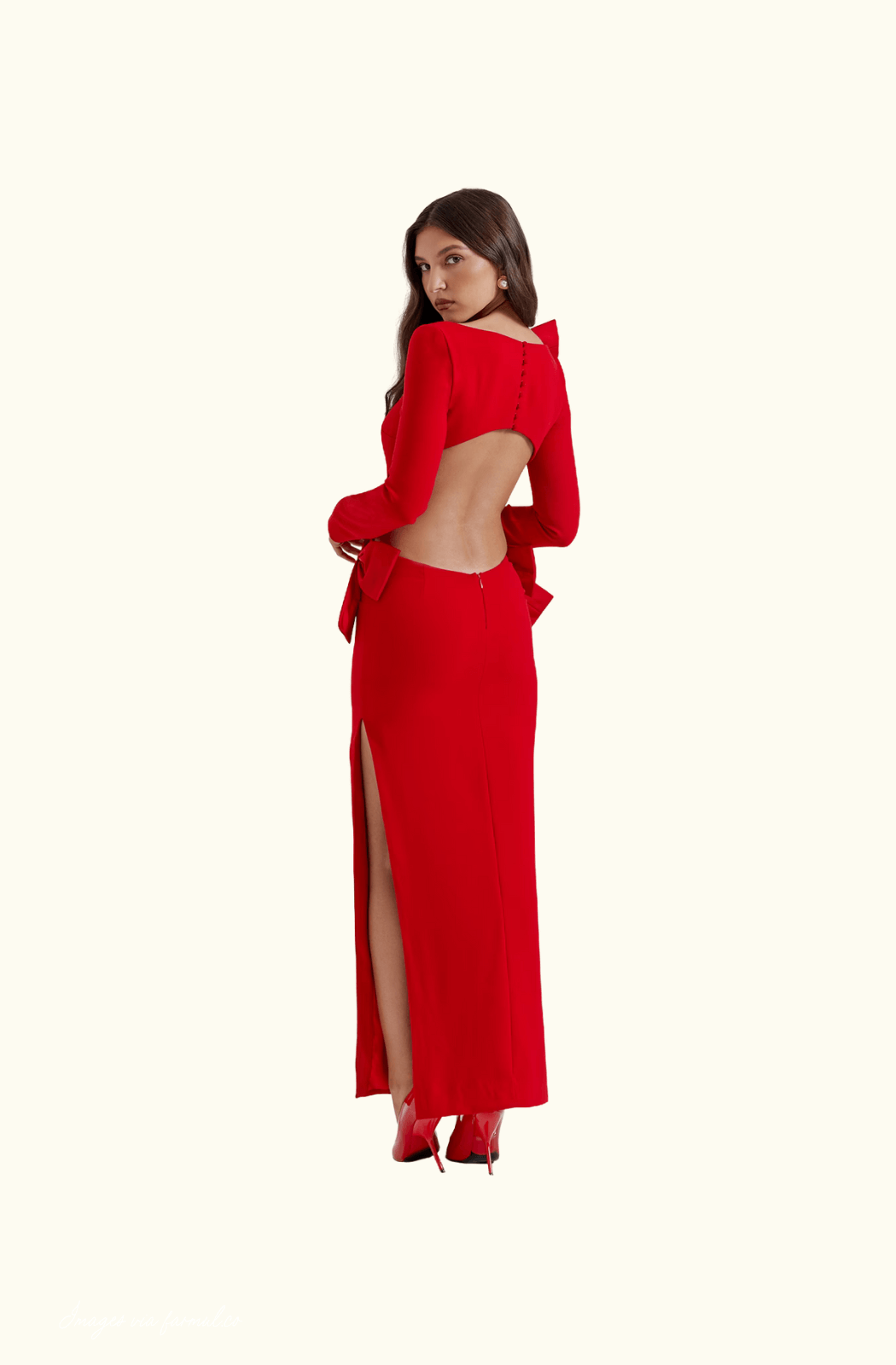 Woman wearing a red dress with an open back and high slit on a white background