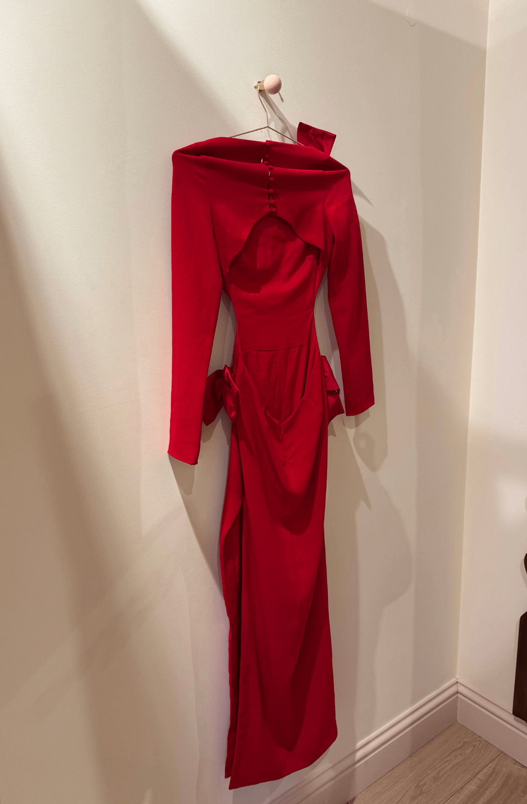 Red open back dress hanging on a wall