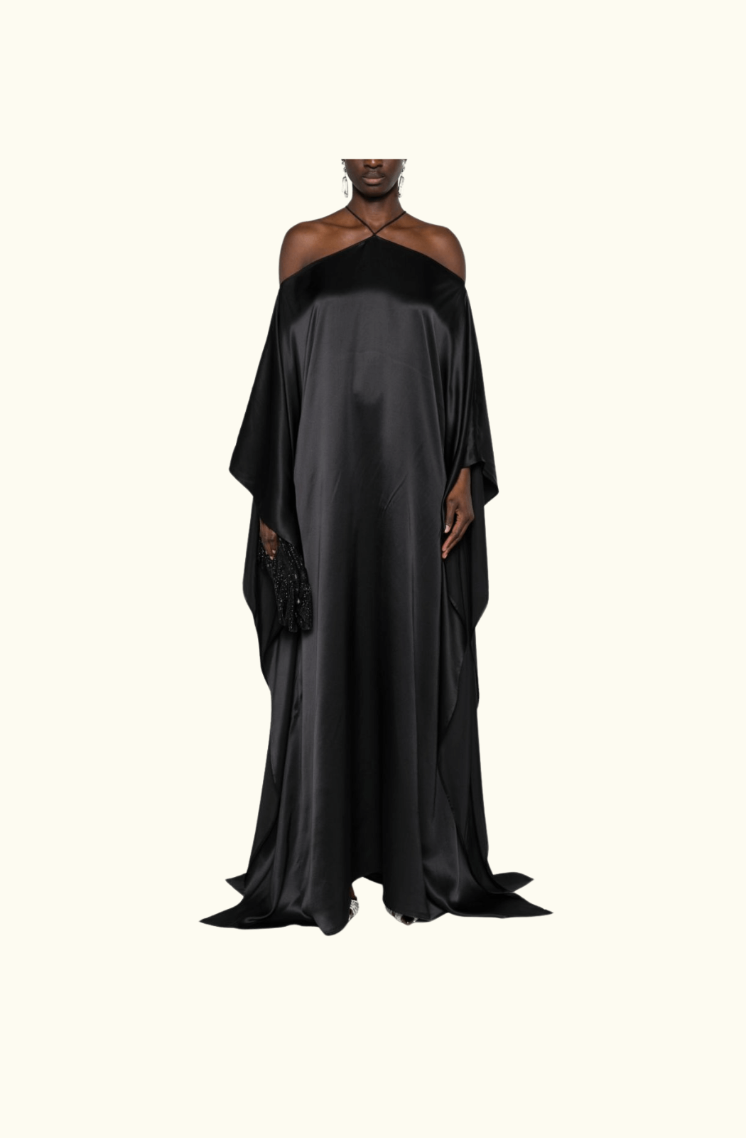 A full front view of the Taller Marmo Sza silk maxi dress, highlighting its luxurious, smooth black silk fabric, halter neckline, and dramatic off-the-shoulder cut with a floor-length hemline.