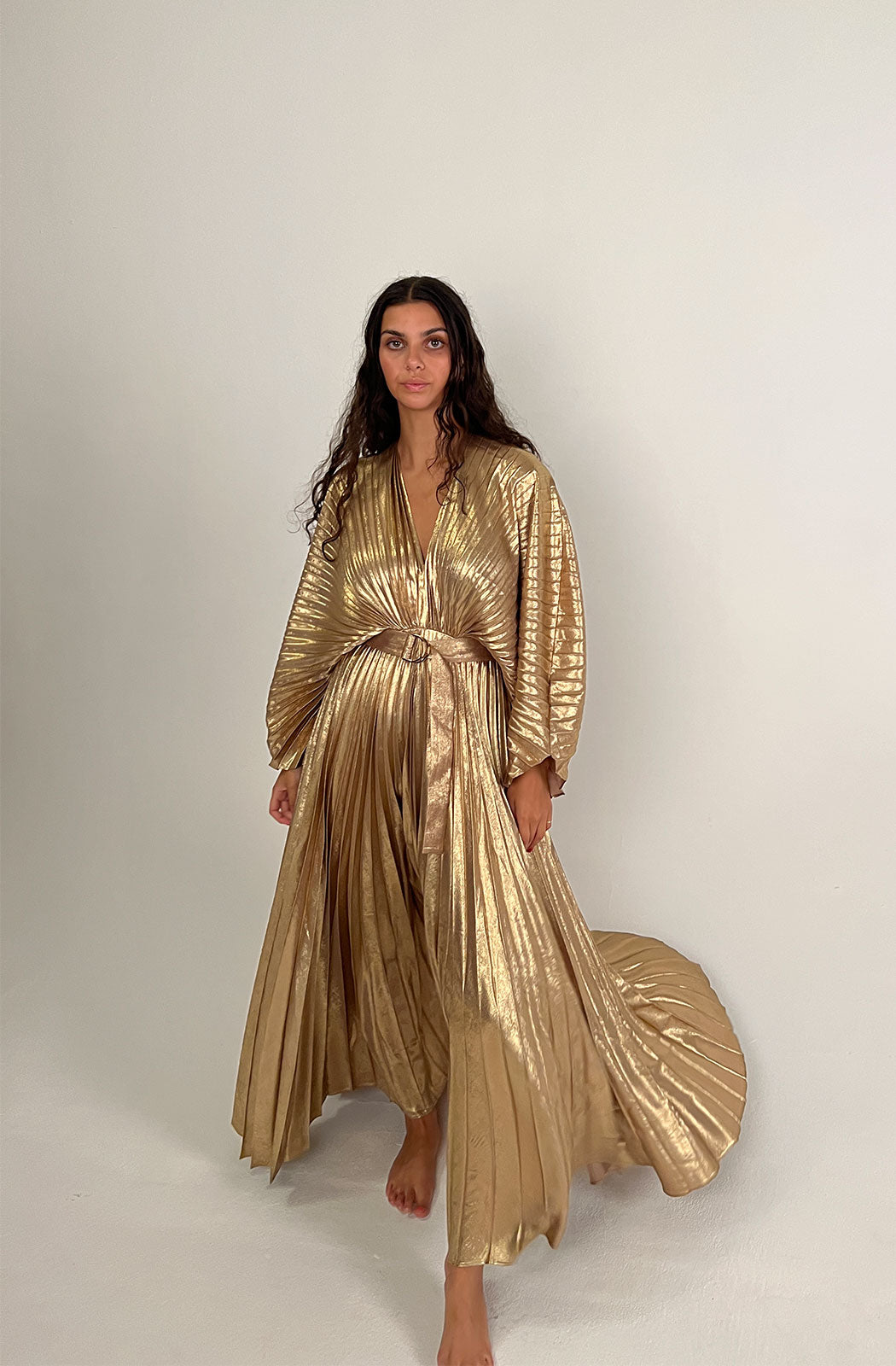 Acler Women's Natural Westover Dress  The Westover Dress in Gold by Acler is a maxi dress crafted in a gold pleated fabrication featuring full length sleeves, a plunging neckline, open back, and statement belt. 100% Polyester.
