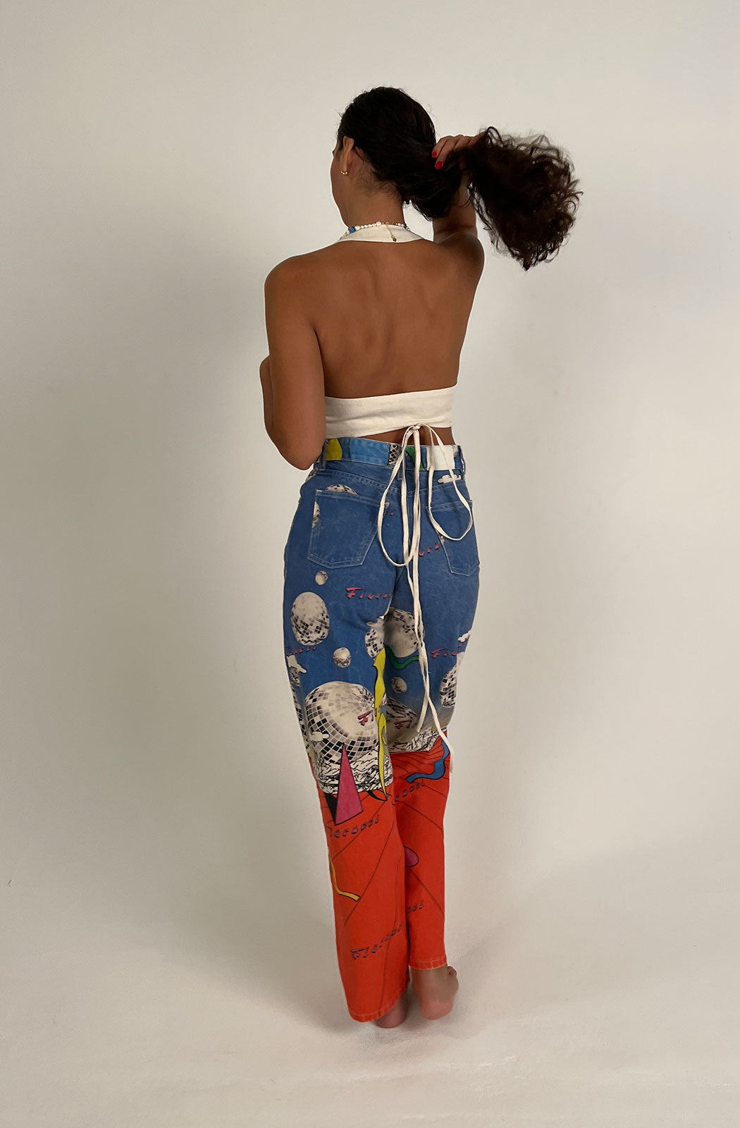 Women's Discoteca Jeans in the all-over multi-coloured discoteca print from the archive. The graphic jeans are high-waisted with a straight leg fit, iconic 5-pocket design, waistband with belt loop and a button and zip fly. Made from hand-crafted, incredibly flattering premium denim. Model back view